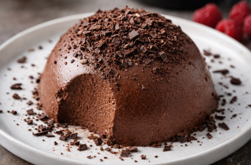 Fotorealistische Schokobombe aus Mascarpone und Bitterschokolade auf einem weißen Teller, mit Schokoladenflocken bestreut, cremige Konsistenz, Dessert ohne Backen.