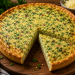 Herzhafter Petersilienkuchen mit goldbraun gebackenem Teig und saftiger Füllung aus frischer Petersilie, Eiern, Käse und Speckwürfeln, angeschnitten auf einem rustikalen Holzbrett serviert.