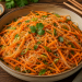Frischer Karottensalat mit Glasnudeln, feinen Karottenstreifen, Frühlingszwiebeln und Sesam, verfeinert mit asiatischem Dressing und frischen Kräutern, serviert in einer rustikalen Schale.