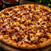 Pulled-Pork-Pizza mit zart gezupftem Schweinefleisch, BBQ-Sauce, roten Zwiebeln, Mais, Kidneybohnen und geschmolzenem Gouda auf knusprig gebackenem Pizzateig.