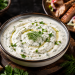Cremige türkische Joghurtsoße mit Knoblauch, Dill und Petersilie, verfeinert mit Olivenöl und Zitrone, serviert in einer Schale auf einem rustikalen Holztisch.